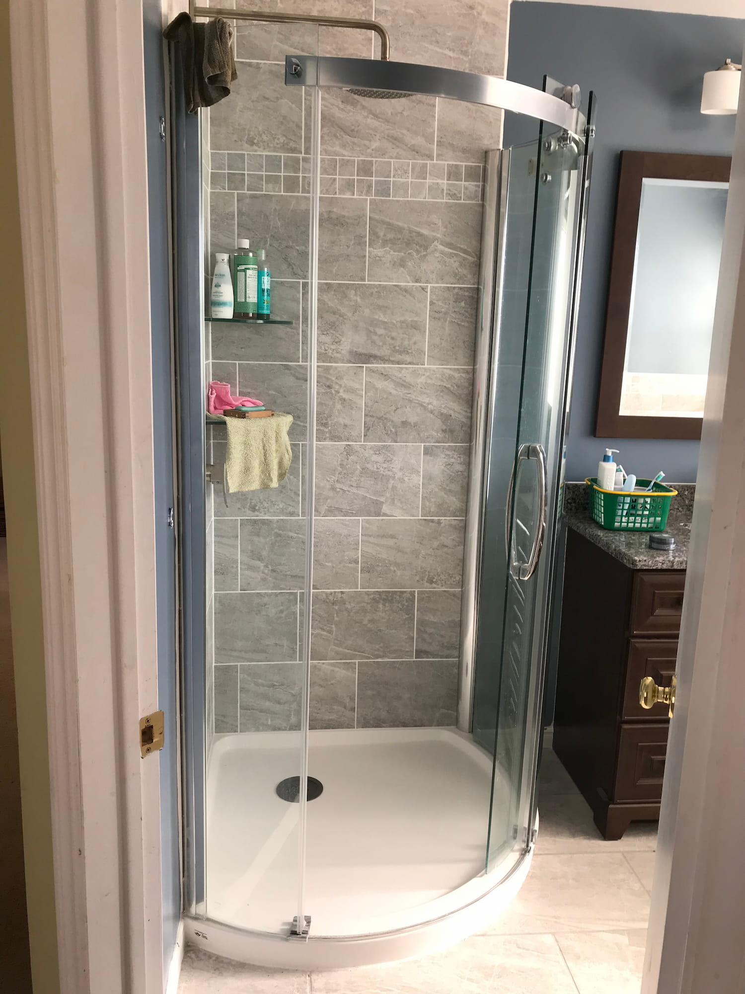 Curved glass corner shower with grey stone-look tile