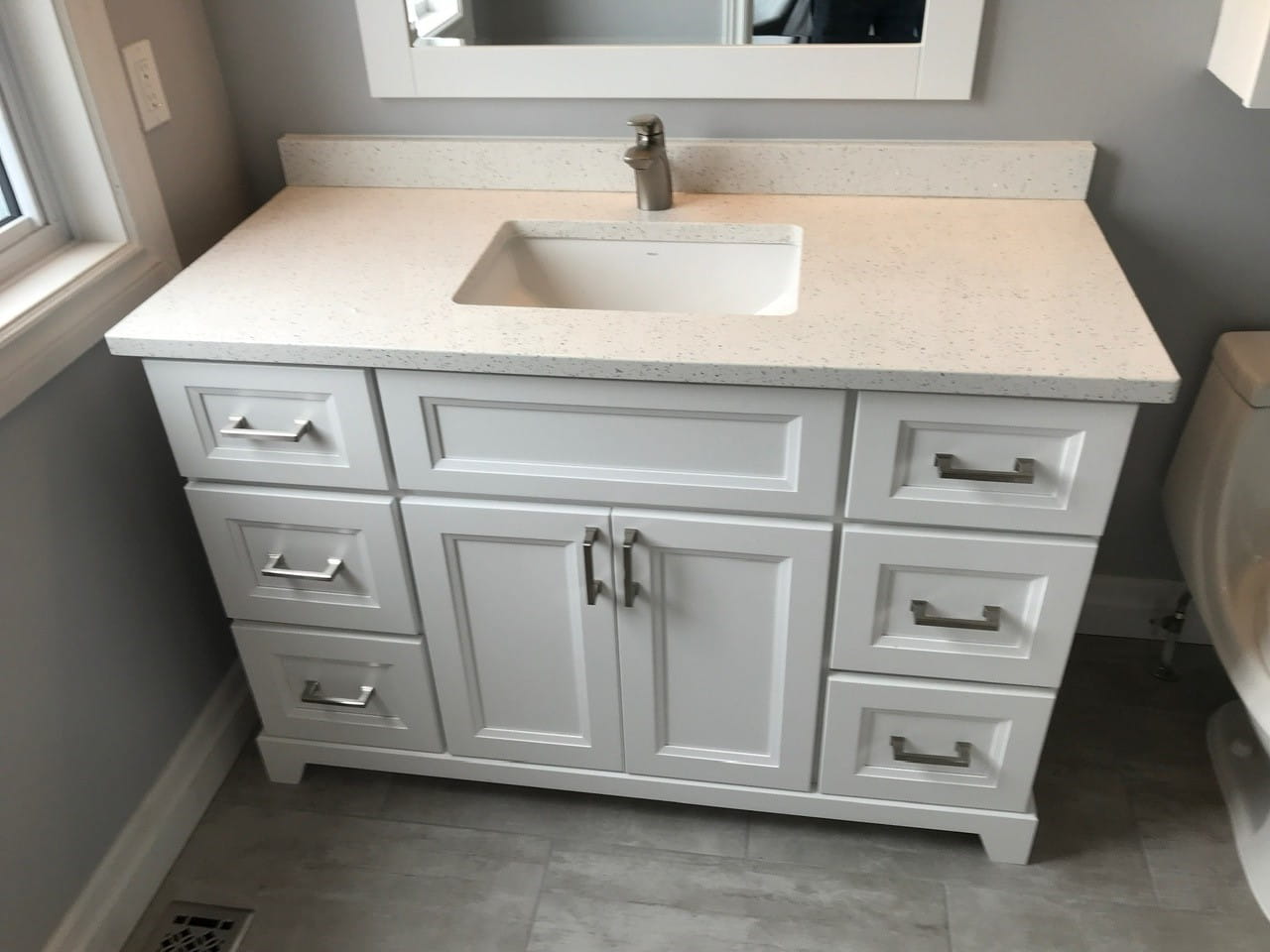 White shaker vanity with speckled quartz countertop and undermount sink