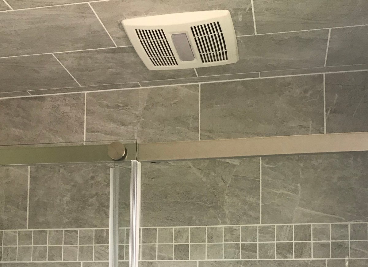 Newly installed ceiling exhaust fan in a tiled bathroom