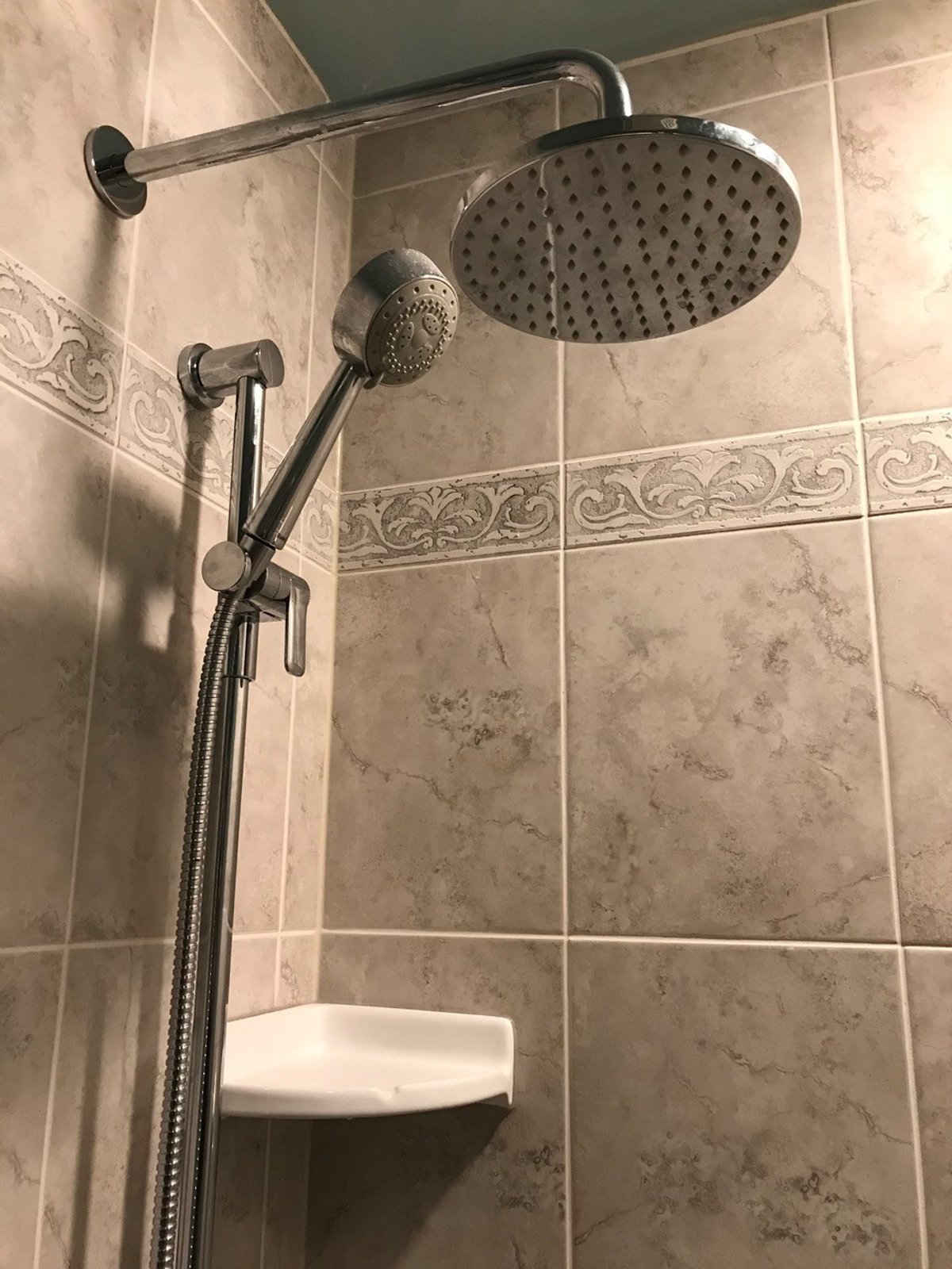 Replacement shower head mounted on tiled shower wall